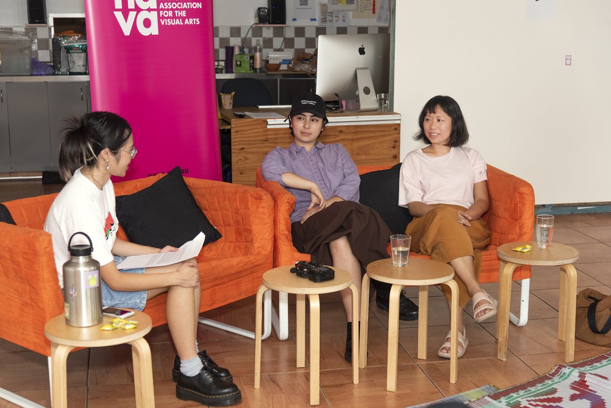 Photo of Emma Pham facilitating an In-Conversation talk with Pari Co-Directors, Tian Zhang and Naomi Segal. A vertical NAVA pink banner stands in the background between them.